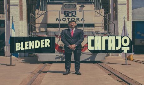 El empresario Augusto Marini junto a una locomotora con el logo de Motora Argentina y los logotipos de los canales de streaming Carajo y Blender.